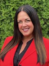 Heidi Ihdi, HLBI - Coldwell Banker Bain realtor. Heidi is a caucasian woman with long brown hair wearing a black shirt with a red jacket and is facing the camera smiling